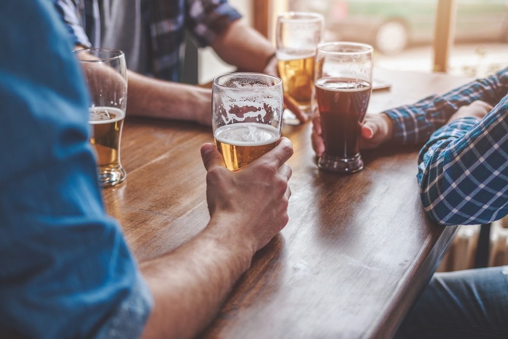 people sitting at wooden table holding beer glasses in their hands