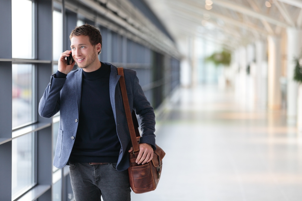 business man traveling through airport while talking on the phone