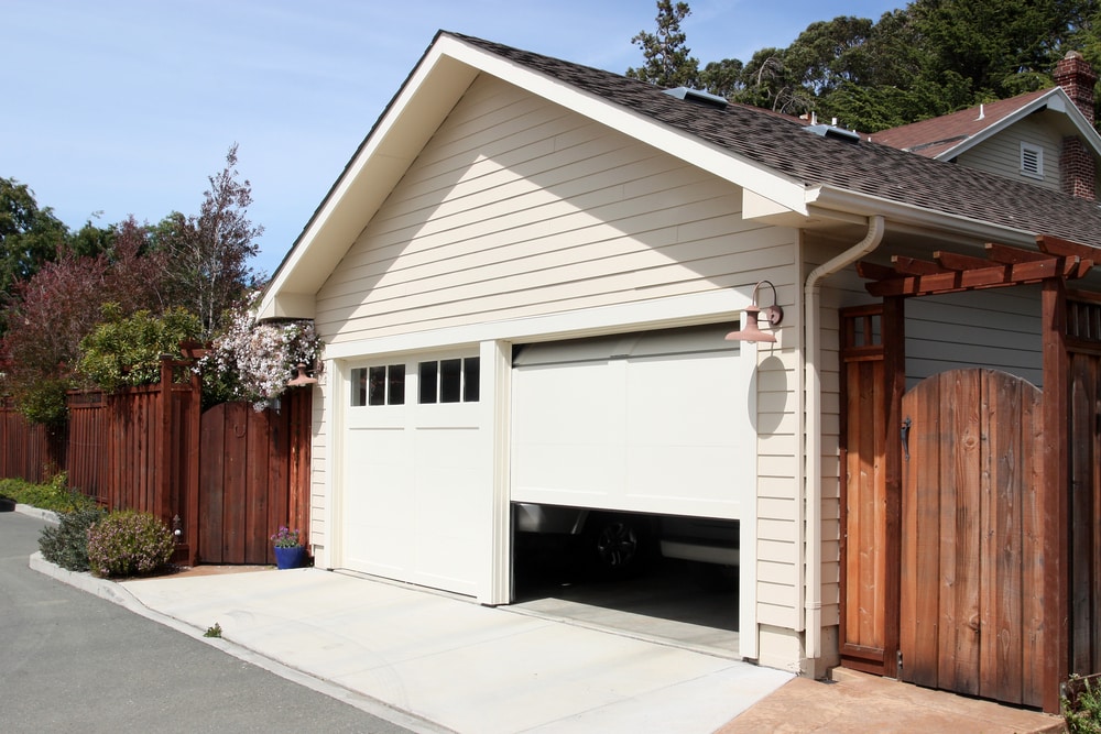 open garage door in suburban white house with wooden fence.