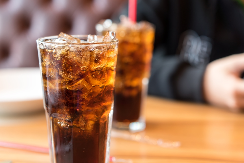 two glasses of coca cola with ice on a wooden table