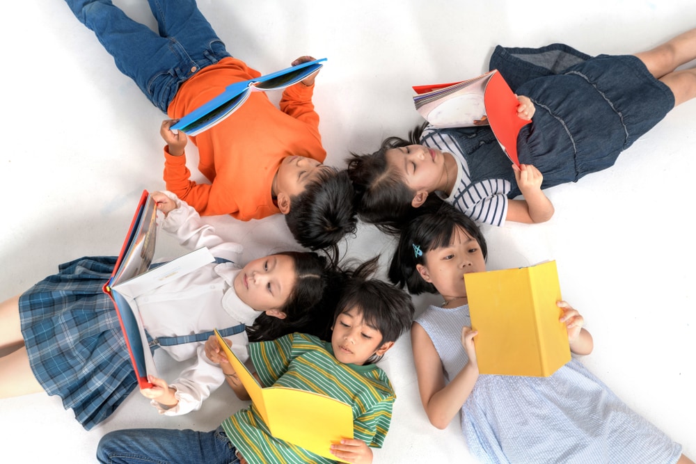 kids sitting floor in circle with their heads together while reading