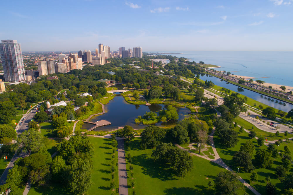 overview of Lincoln Park zoo next to the lake. There are lots of city buildings to the left and wide open water to the right 
