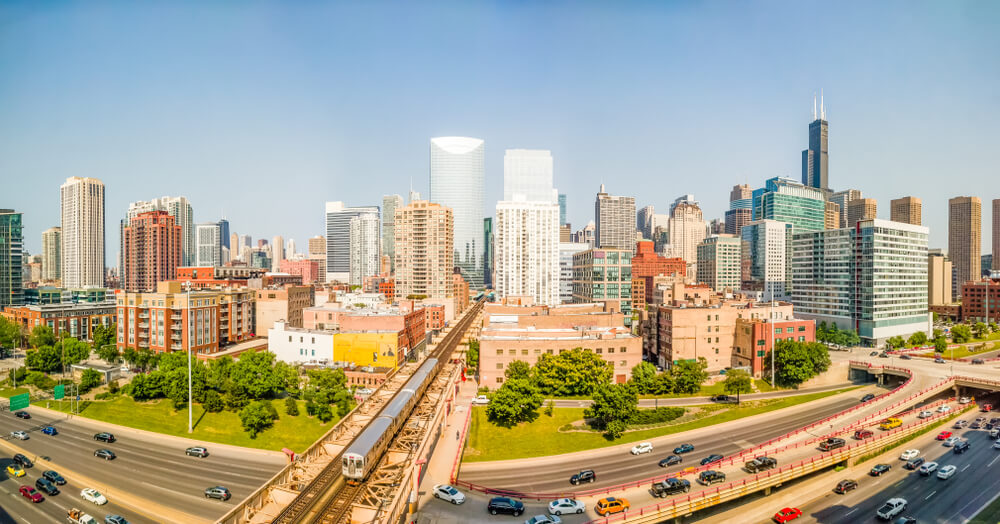 view of Chicago's West Loop with lots of buildings and city skyline in the background with a large highway and lots of cars in the foreground