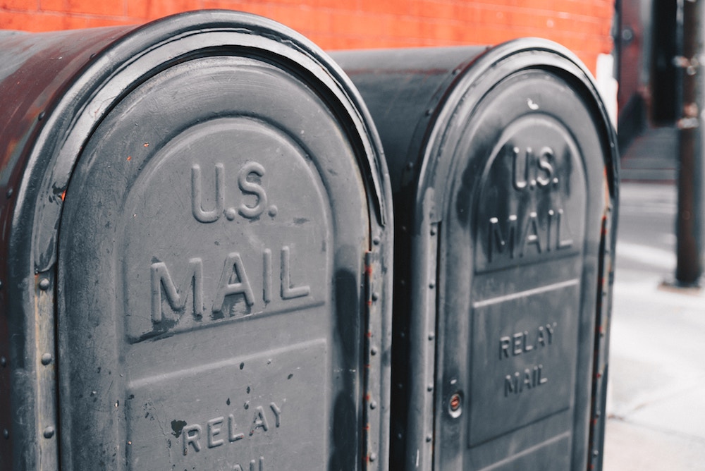 two large dark blue U.S. mail boxes on a city street 