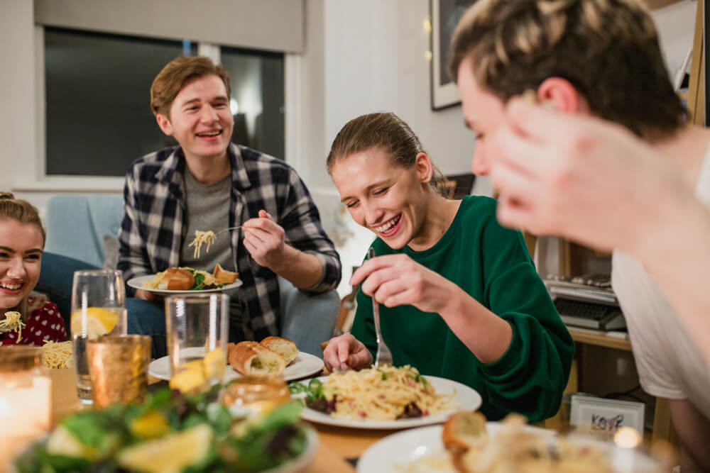 friends sharing dinner together eating spaghetti