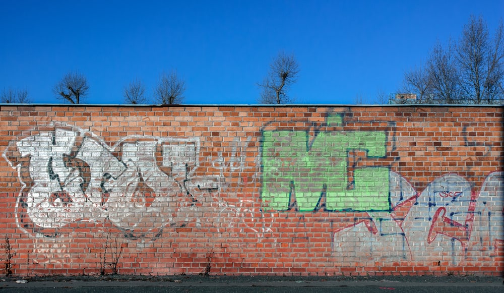 brick wall covered in graffiti in front of a blue sky