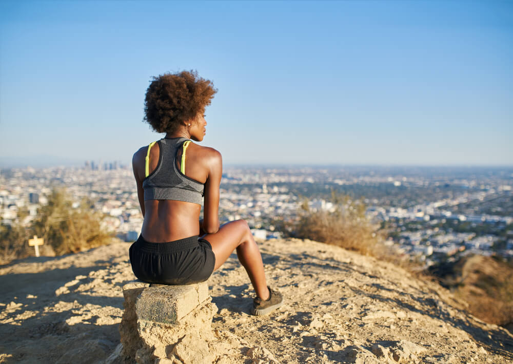 woman sits on a rock while hiking outdoors in los angeles
