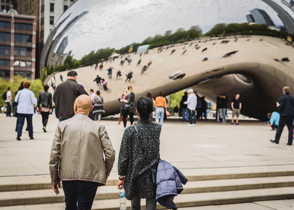 Tourists and locals standing around the Bean landmark in Chicago