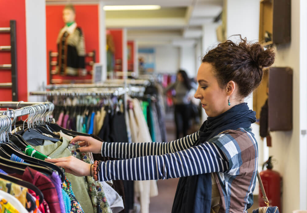 woman looking at some clothes in a thrift store