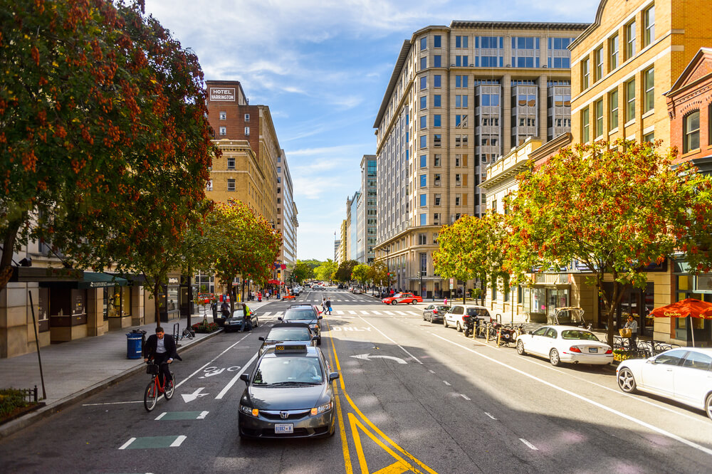 a street in downtown dc with buildings and cars waiting at a traffic light