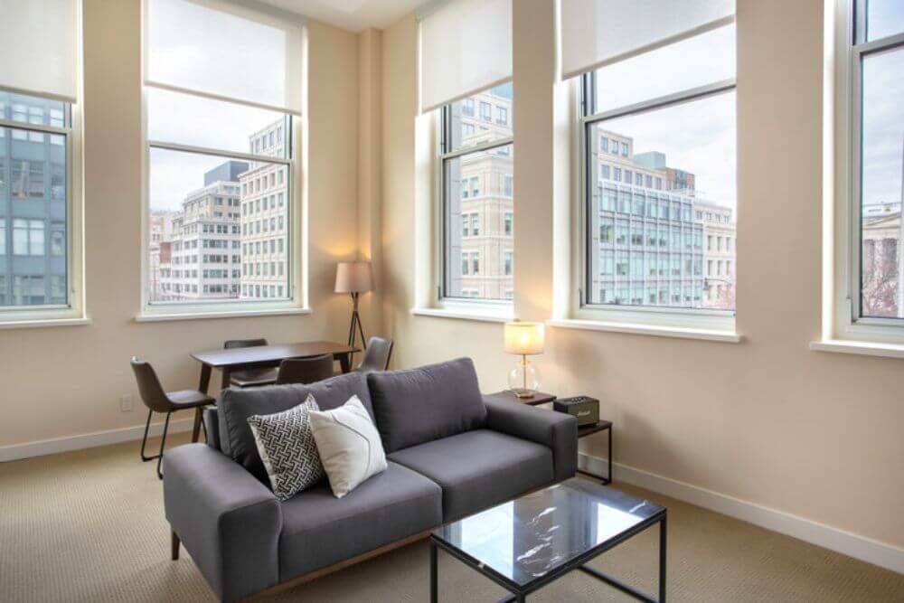 neighbourhood legal services a furnished blueground living room with a grey couch and big windows