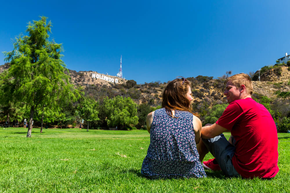 couple sitting on the grass in a close to the Hollywood sign