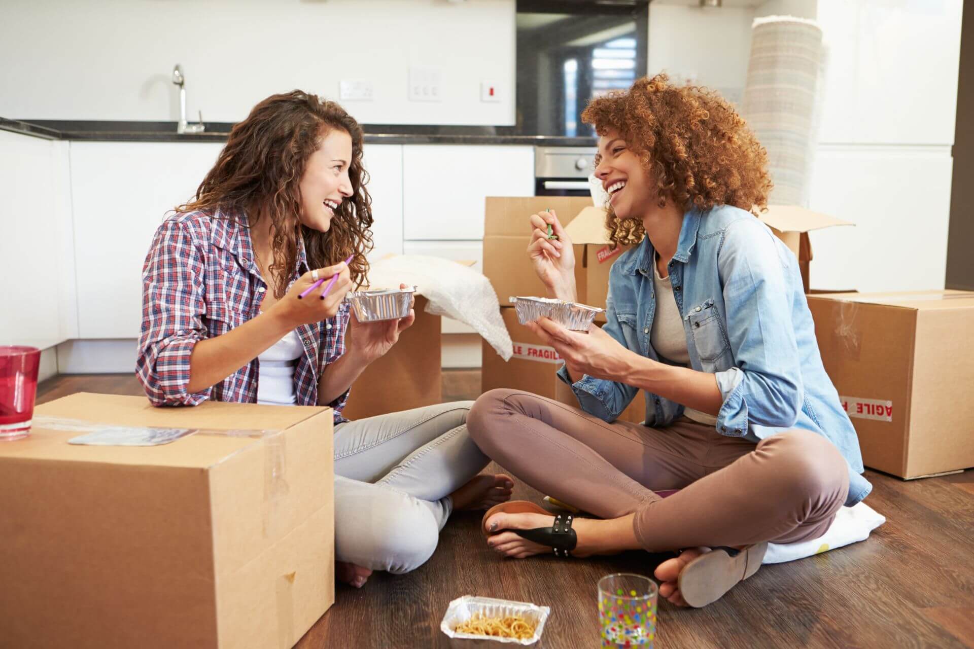 food delivery in los angeles two girlfriends having lunch inside their apartment sitting next to moving boxes