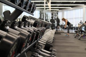 gyms in Chicago set of dumbbells on a weight rack with woman in the background