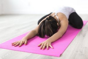 woman laying down on her yoga mat in child's pose during class