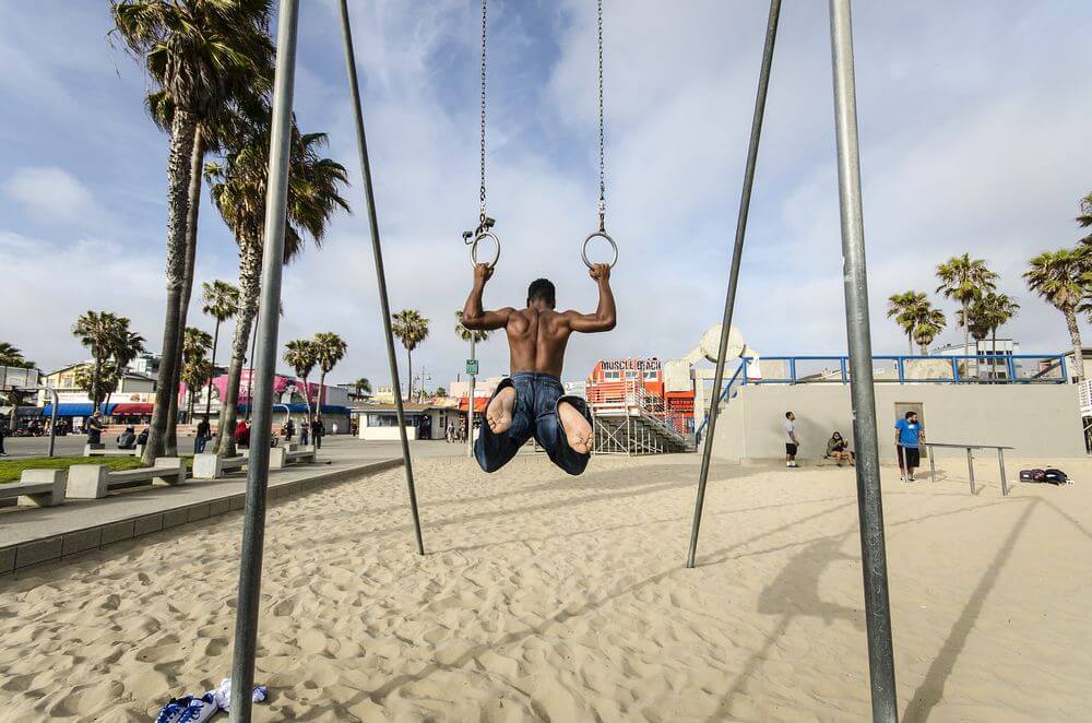 gyms los angeles man stretching on the rings doing pull ups on muscle beach in los angeles california
