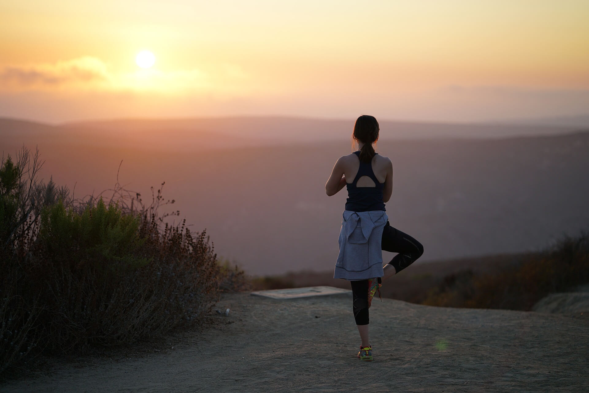 Woman in sports clothing doing a yoga pose on a mountain in Los Angeles