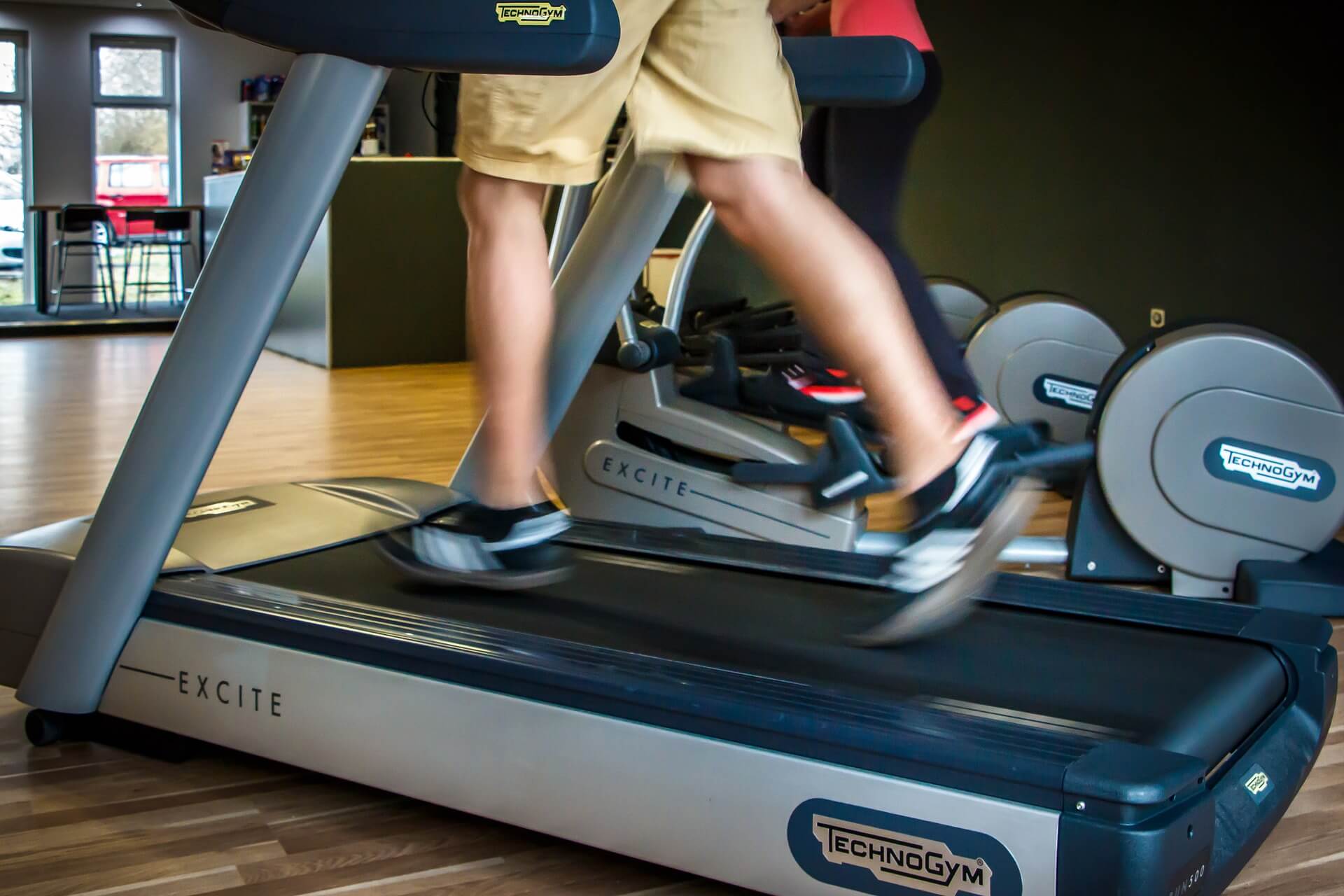 a man wearing brown shorts and black and white sneaker is running on a treadmill 