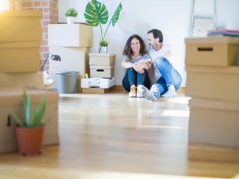 couple on moving day sitting on the ground with boxes