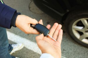 man handing the keys of a car to a person who rented it