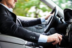 man wearing a business suit driving a car 