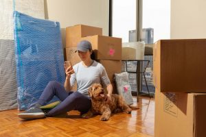 girl sitting on the floor with her dog surrounded by boxes