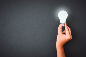 save money on electricity mans hand holding an LED lightbulb