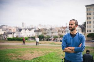 man standing with his arms crossed on a field in Alamo Square