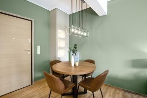 blueprint blueground mid century modern corner of room with green walls and brown leather and wood dining set