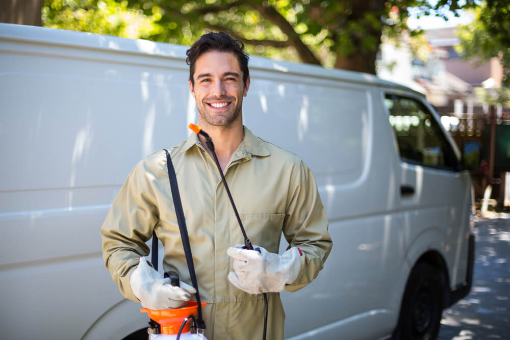 smiling exterminator in front of a white van 