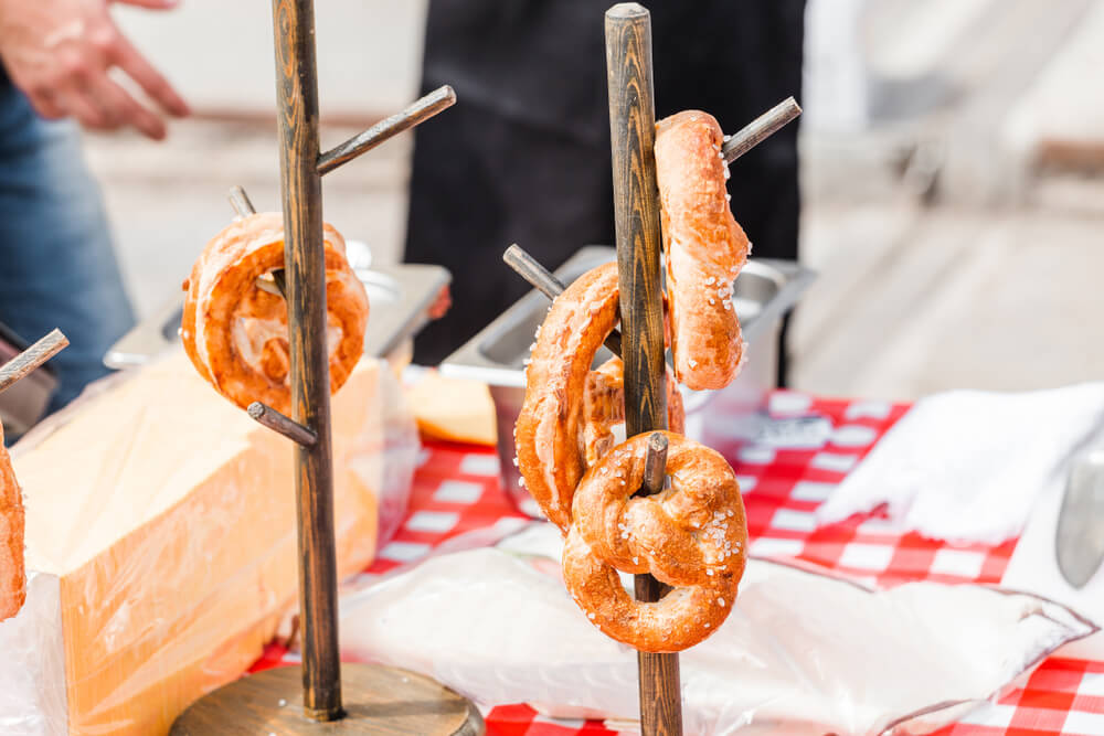 large salty pretzels on display on a table with a red and white tablecloth at a street food festival 