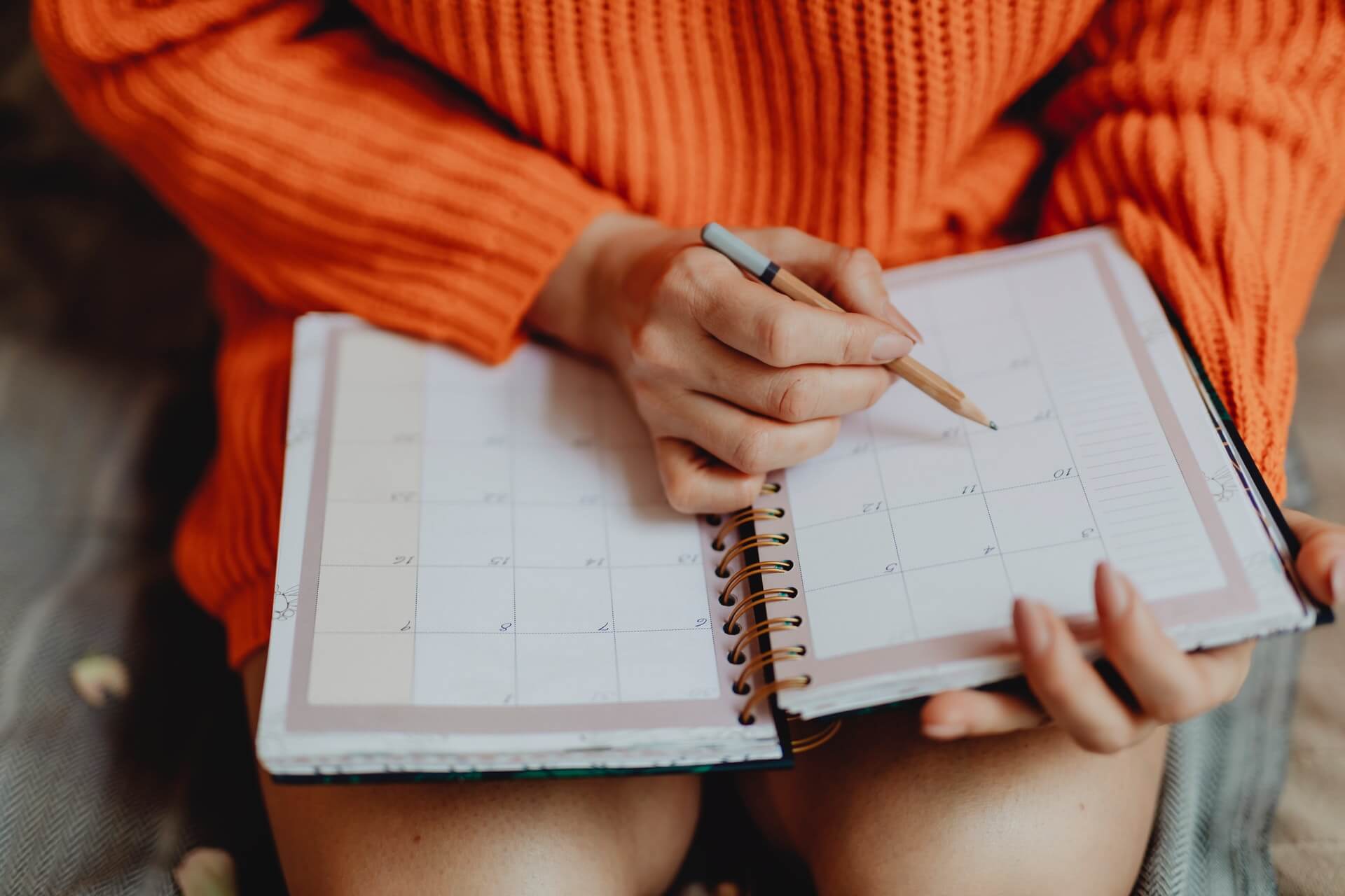 organize work schedule Woman wearing an orange dress sitting with a paper schedule notebook 