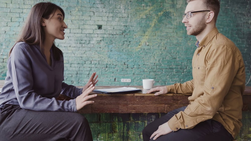 Male and female sitting in conversation over a coffee 