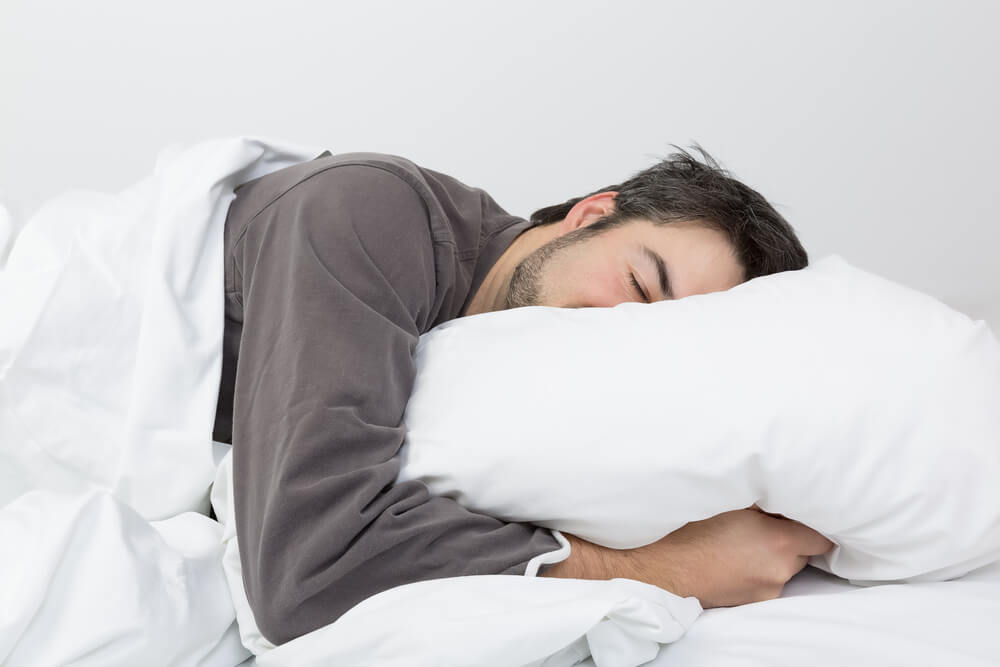 Man resting his head on a white bedroom pillow