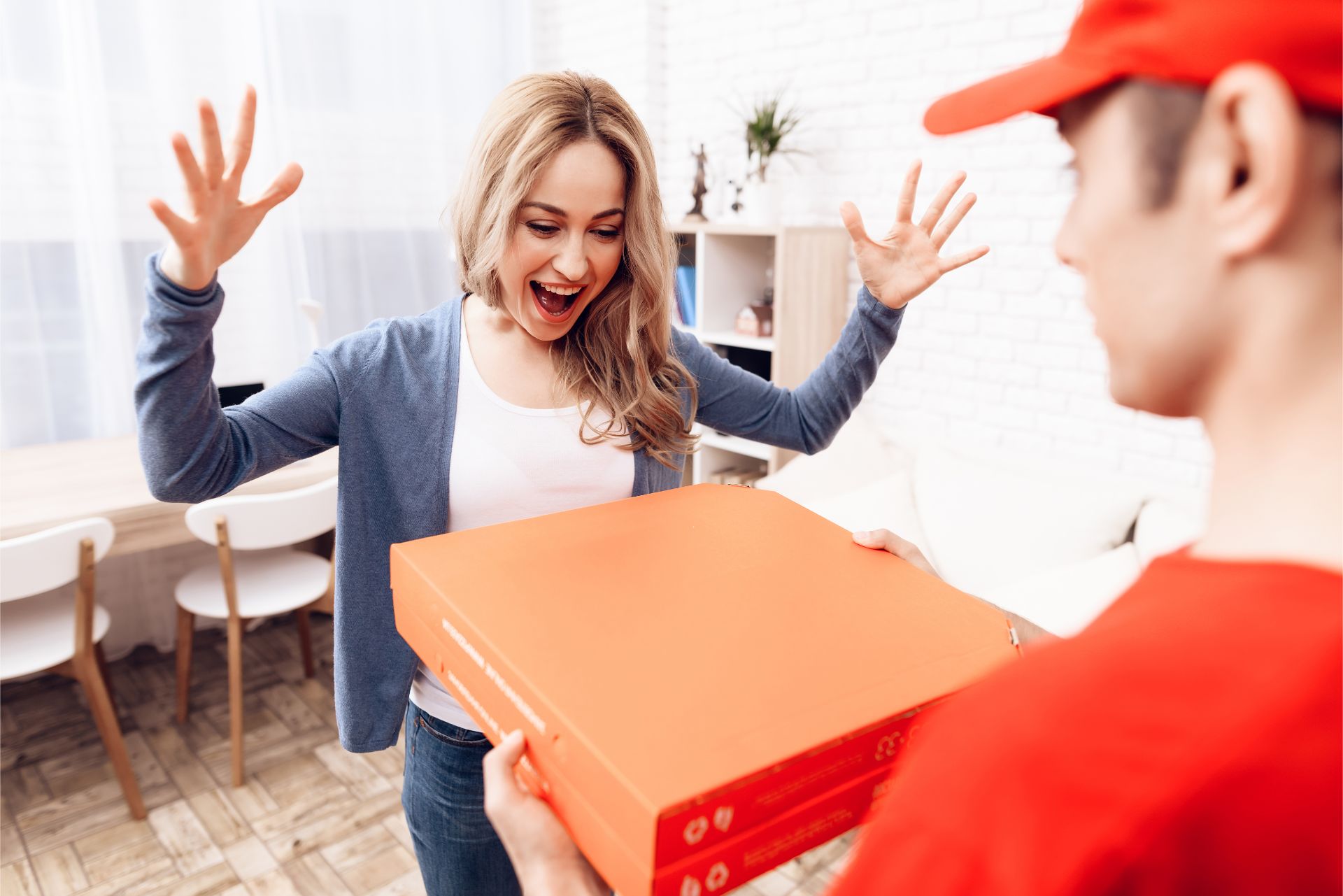 Happy woman opening the door to a delivery man with a pizza box