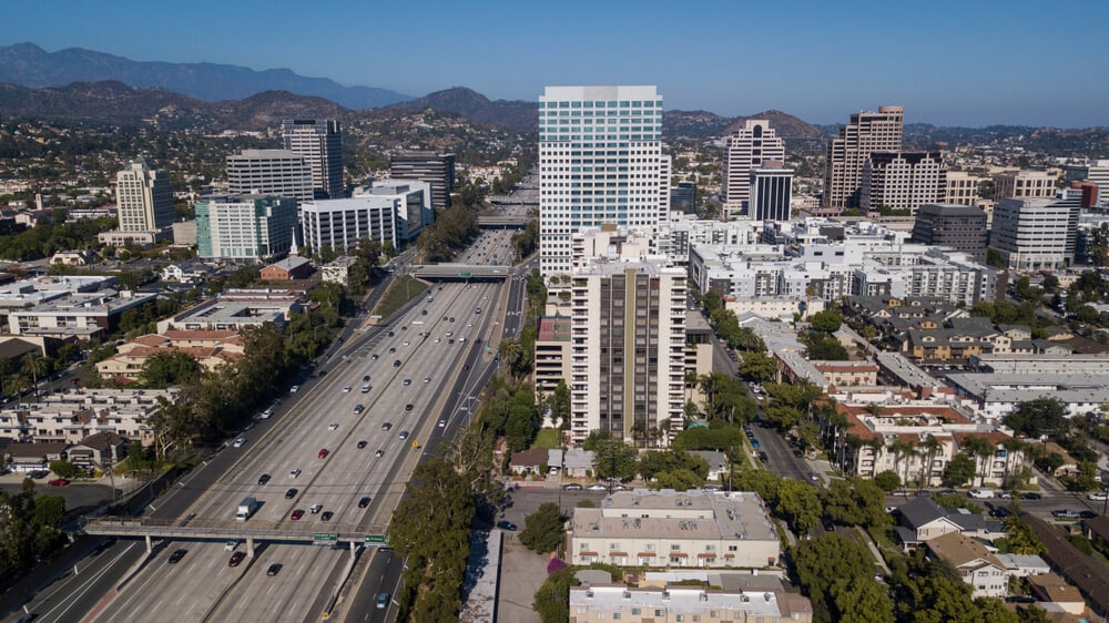 A large highway with many cars on it with tall buildings on either side. It is a view of Glendale, California from above.