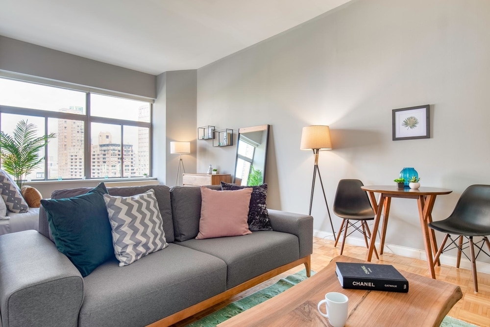 furnished studio for rent in NYC green rug grey couch