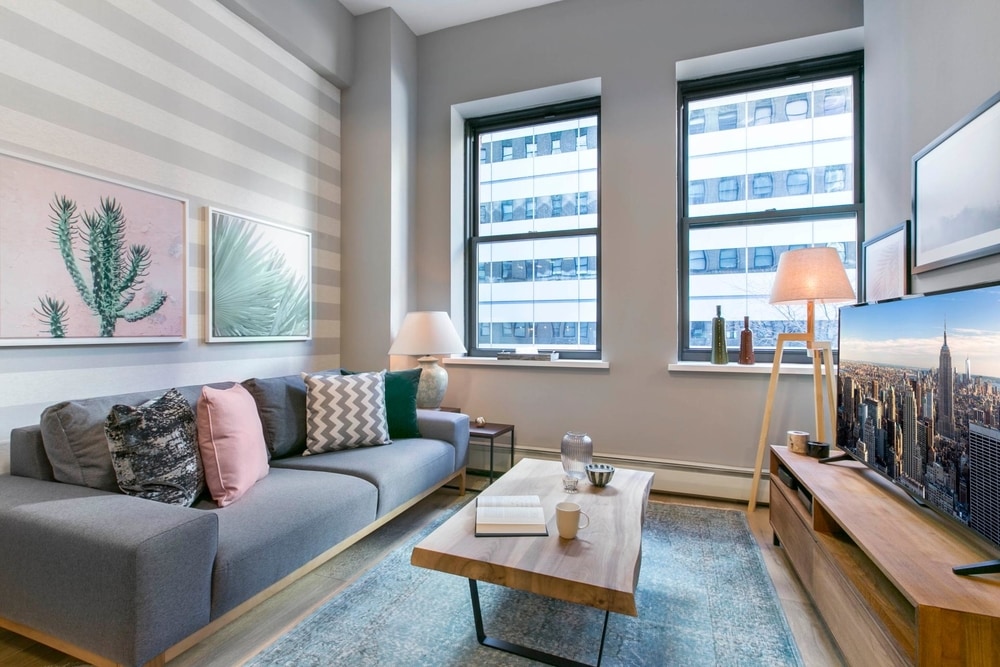  grey striped walls with cactus painting on wall and a grey couch and a wooden coffee table
