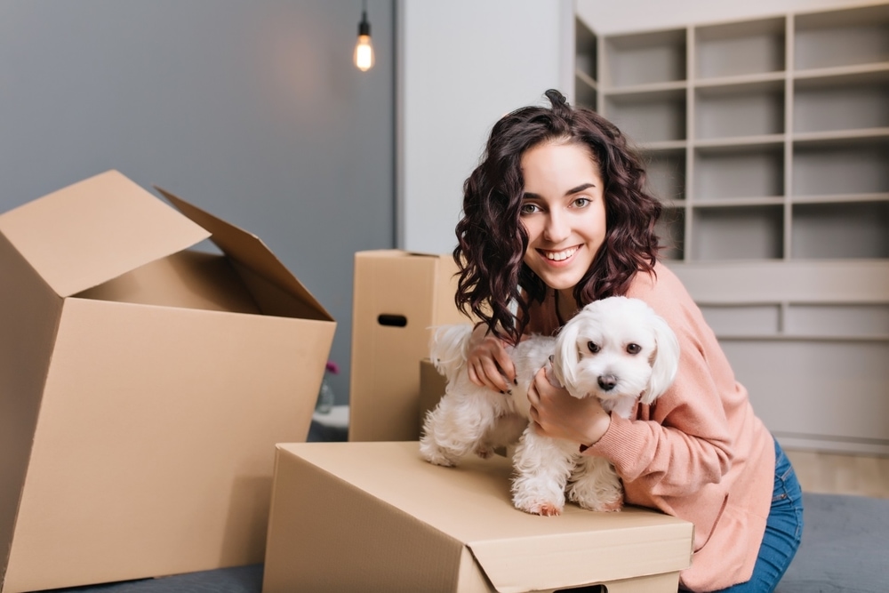 Lady with a small dog in an apartment with boxes