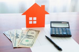 cash calculator pen spreadsheet and orange paper house on a table