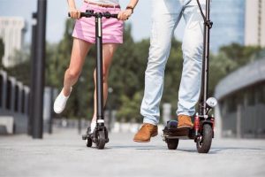 two people riding bird scooters side by side