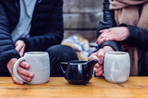 a couple holding tea cups on a table
