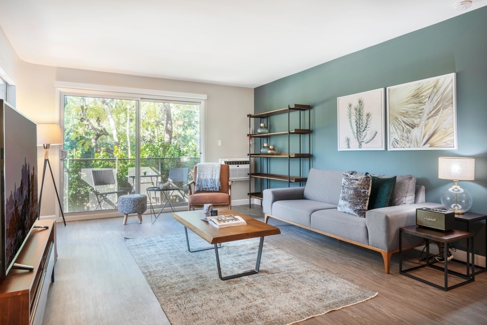 blueprint blueground short term rental los angeles living room grey couch against teal wall and palm leaves print on wall