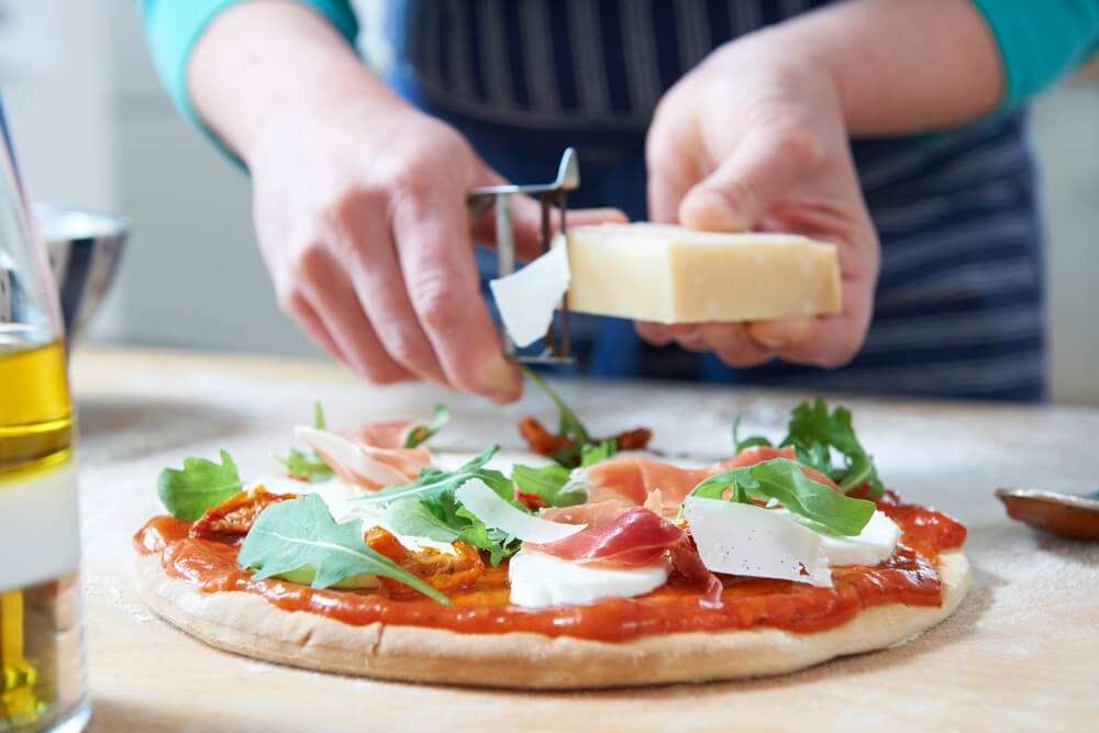 making a pizza at home with shaved cheese