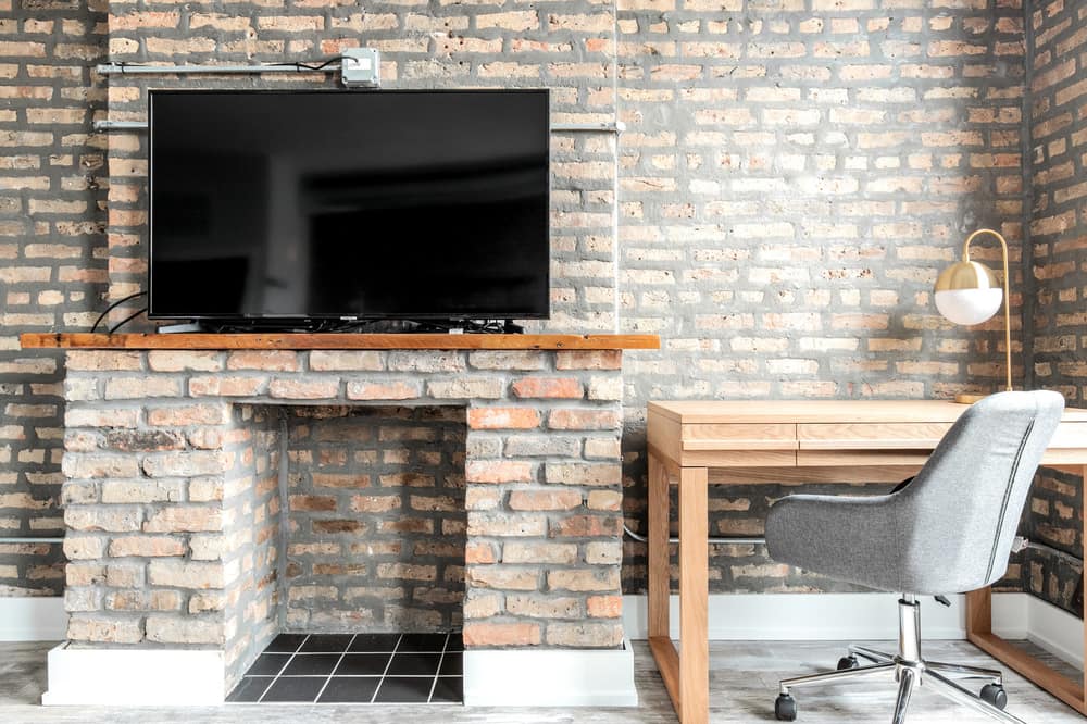 work desk beside a fireplace with TV on mantel