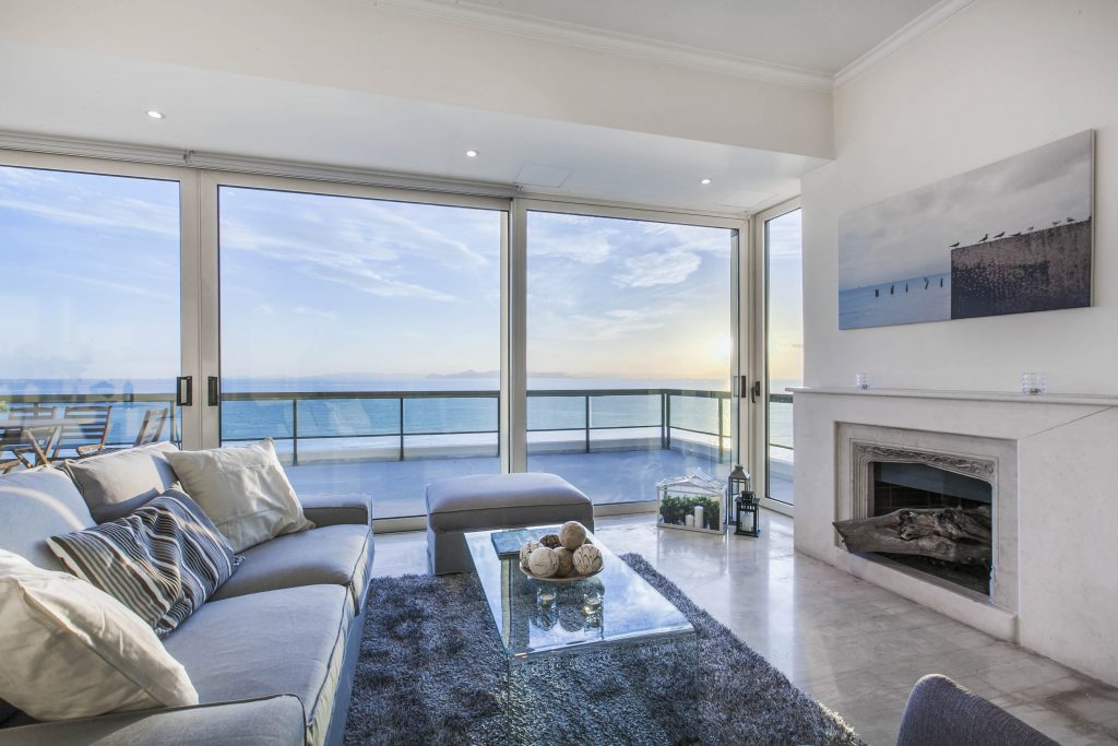 Spacious living room with modern furniture and a big fireplace in Palaio Faliro, Athens featuring a stunning sea view