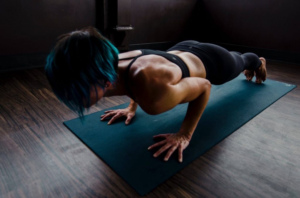 a woman is doing a plank on the green fitness mat