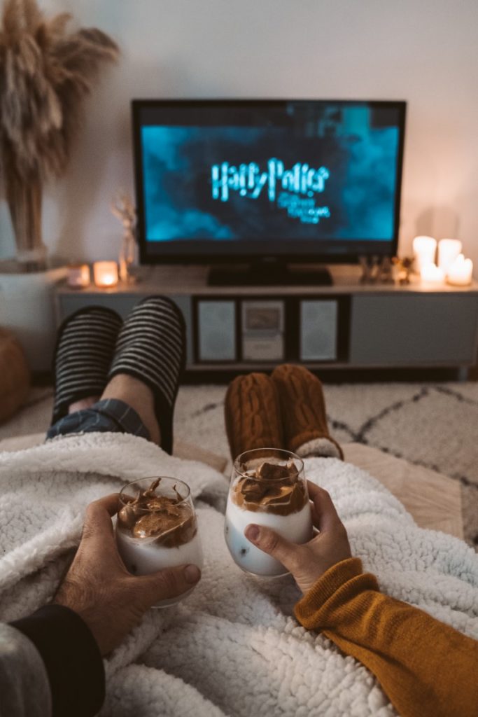 a couple under the blanket drinking hot chocolate while watching the Harry Potter movie