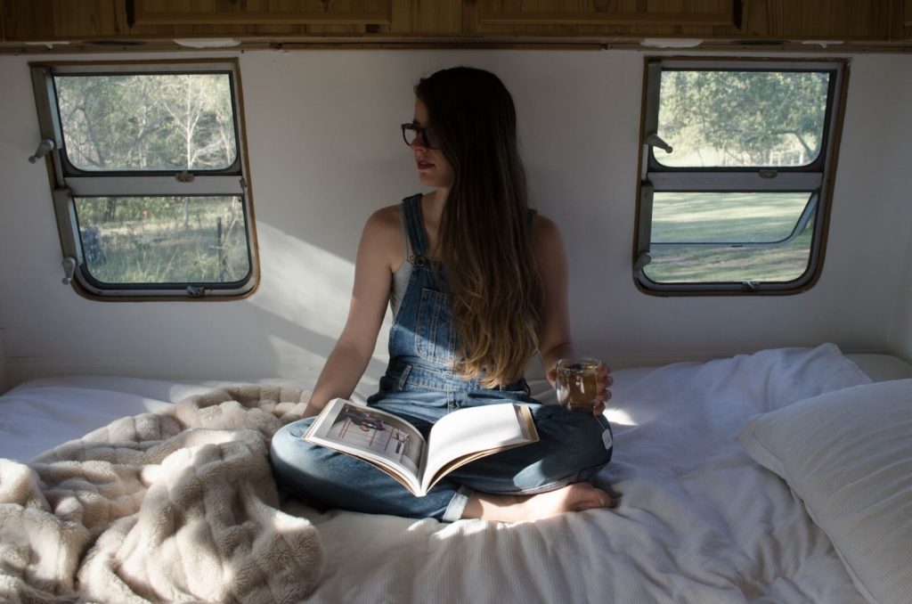 A girl reading a book inside a caravan
