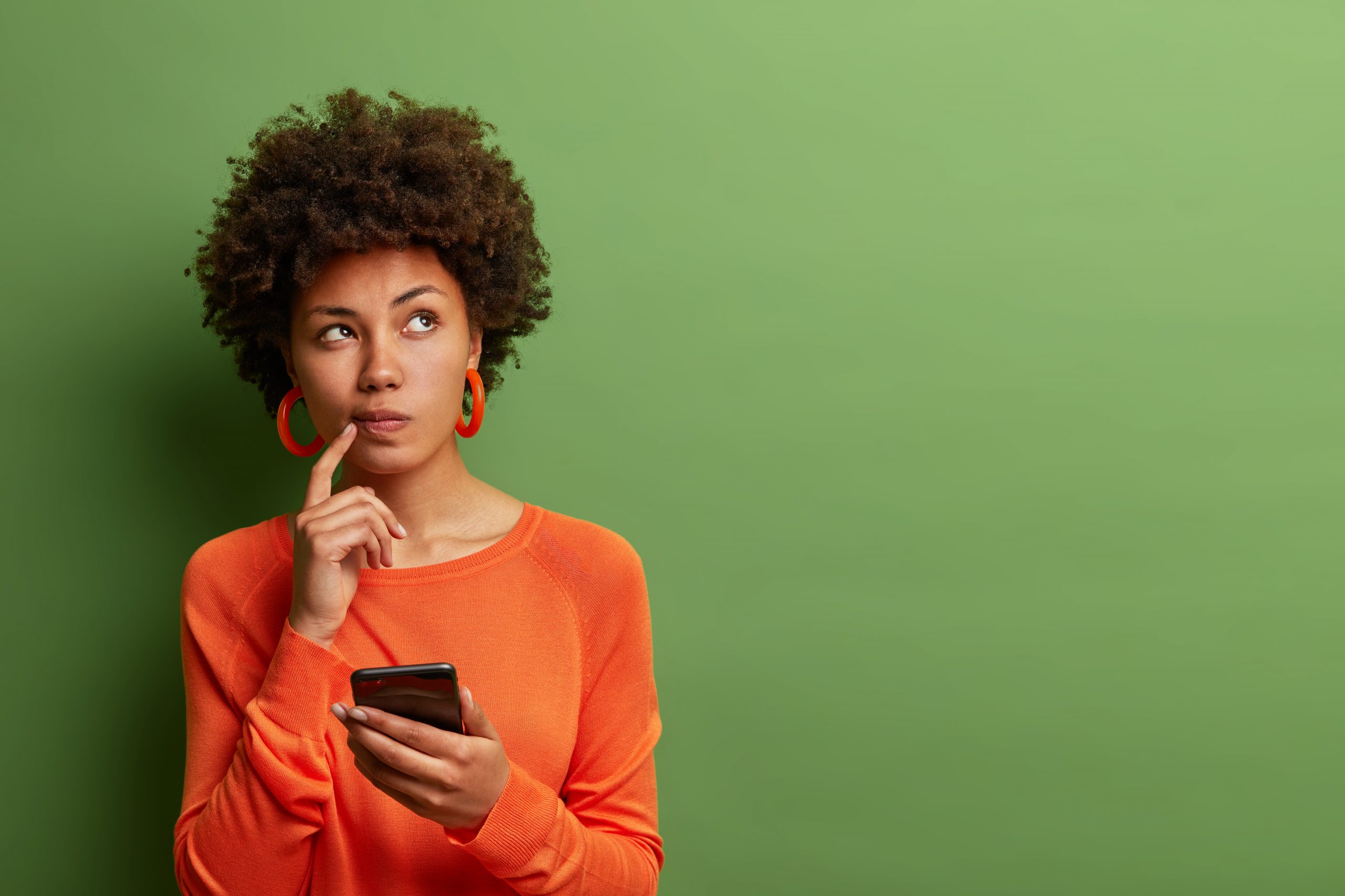 Woman thinking with phone in hand